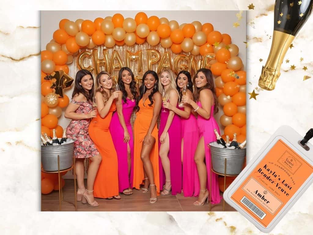 Vibrant women celebrating with champagne at a birthday party, stylish dresses, orange and pink decor, festive atmosphere.